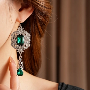 Detailed side view of vintage palace style earrings with emerald green gemstones