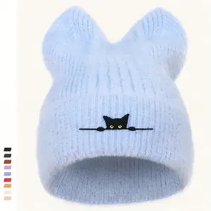 Detailstruktur der hellblauen Strickmütze mit Katzenohren und Stickerei-Augen