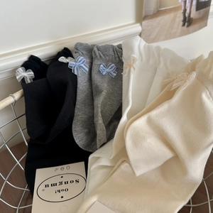 Detail of ribbed crew socks set with elegant chiffon bow accents in neutral colors