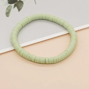 Detail van saliegroene heishi kralenarmband met flexibele elastische kleischijfjes