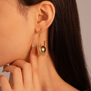 Detailed view of textured gold C-shape hoop earrings with a polished metal sphere