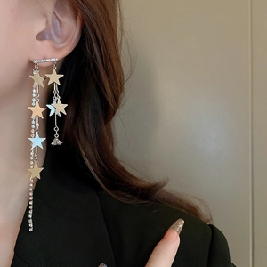 Détail de boucles d'oreilles à longs pompons avec strass brillants et étoiles argentées