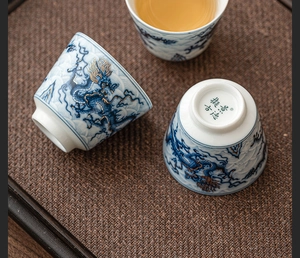 Detail of Jingdezhen ceramic teacups featuring blue and white dragon motifs and gold accents