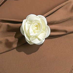Close-up of white 3D camellia flower appliqué on a brown drawstring swimsuit