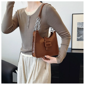 Detail of brown leather underarm bag with woven edges and decorative square buckle