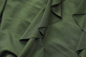 Détail macro du tissu en maille vert foncé montrant la texture dense et le drapé fluide