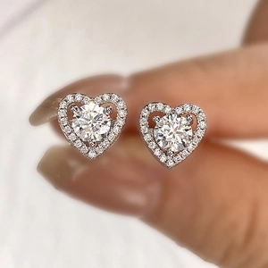 Macro shot of heart-shaped moissanite stud earrings in 925 sterling silver held by fingers