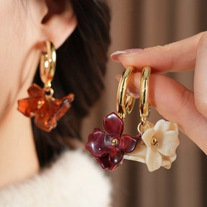 Detail view of resin flower petal earrings in amber, burgundy and cream with gold hoops