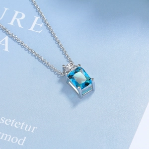 Macro detail of rectangle blue zircon pendant on silver chain with sleek geometric design