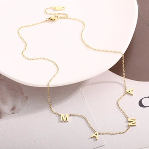 Elegant gold-plated stainless steel MAMA letter necklace on a minimalist ceramic plate