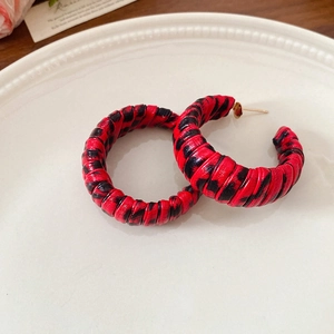 Detail of leopard print hoop earrings with woven texture on a decorative white plate