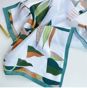 Detail showing botanical patterns and green rolled edges on white silk scarf