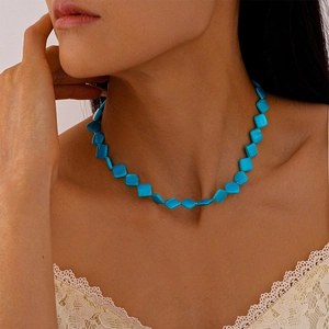 Primo piano della collana girocollo con perle geometriche turchesi sul collo