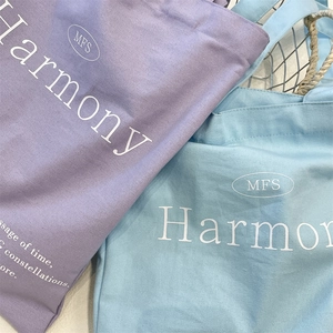 Detail of Harmony letter printed canvas tote bags in purple and light blue colors