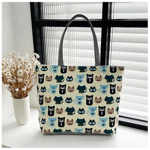 Detail of canvas tote bag with colorful cartoon cat print and sturdy grey handles