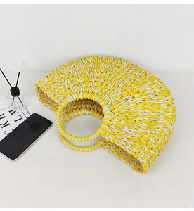 Detailed view of handmade woven straw tote bag with round handles on white background