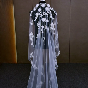 Detailed view of white bridal veil with 3D floral lace embroidery and scattered pearls