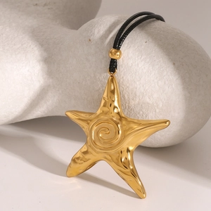 Macro detail of a golden starfish pendant with hammer-textured surface on black cord