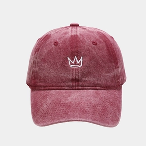 Detailed view of crown embroidery and distressed texture on washed wine red baseball cap