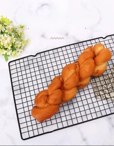 Close-up of golden bread on black carbon steel non-stick cooling rack with rectangular mesh