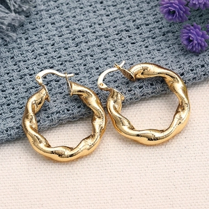 Details von klobigen goldenen Creolen mit gedrehter Metallstruktur im Vintage-Stil