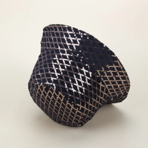 Dettaglio delle paillettes scintillanti e del motivo a rombi sul cappello da pescatore