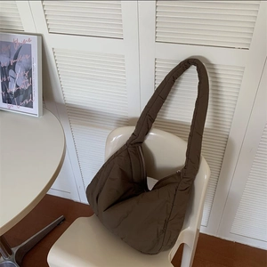 Detail of dark brown quilted puffer tote bag with soft sponge padding on a white chair