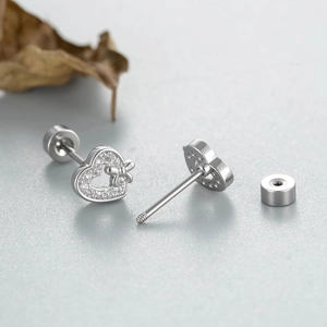 Exquisite bow heart silver stud earrings with sparkling cubic zirconia on a leaf background