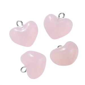 Macro detail of four translucent pink heart pendants with silver metal rings for DIY jewelry
