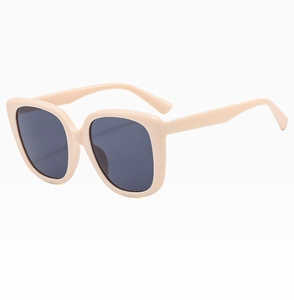 Detail view of cream oversized square sunglasses with black UV protection lenses