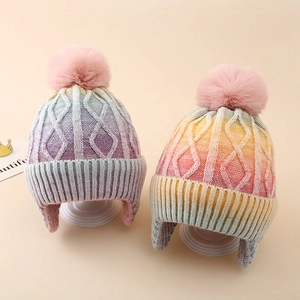Detail of kids cable knit winter hats with pompom and colorful tie-dye gradient design