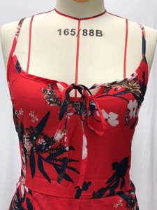 Detail view of red floral summer dress featuring bust tie-knot and thin spaghetti straps