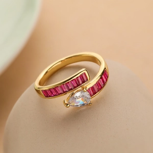 Detail of gold-plated ring featuring red zircons and a pear-shaped white main stone