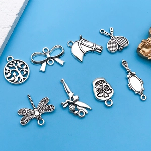 Detailed view of assorted vintage silver alloy charms with butterfly and tree of life motifs