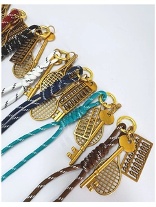 Detail of hand-woven phone straps with vintage golden tennis rackets and abacus charms