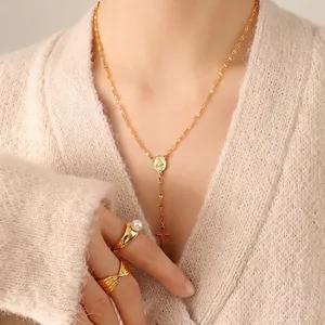 Gold plated rosary necklace with cross pendant and pearl ring on knit cardigan