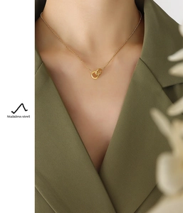 Close-up of interlocking gold-plated rings on stainless steel necklace worn with blazer