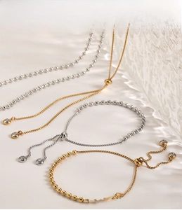 Detail of adjustable stainless steel bead bracelet with zircon pendants and PVD gold plating