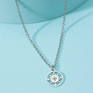 Close-up of compass pendant with hollow design on stainless steel necklace