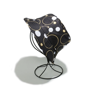Détail d'un chapeau bob noir avec motif chaîne dorée et pois blancs vintage