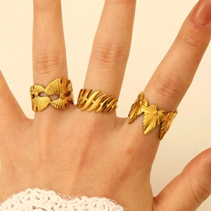 Detailed view of three golden irregular plant-shaped rings worn on a hand