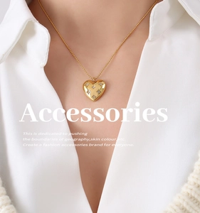 Detail of a gold heart pendant necklace with starburst crystals on a sweater