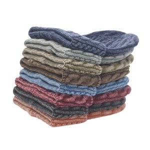 Detailed stack of eight colorful cable knit beanies showing texture and variety