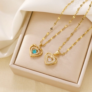 Golden heart wing projector necklaces with blue and clear gemstones on silk background