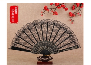 Detailed view of elegant black lace folding fan with golden patterns on black ribs