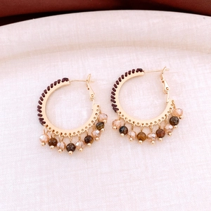 Detail of bohemian hoop earrings with brown woven thread and faceted glass beads