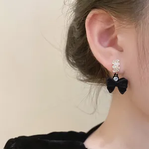 Détail de boucles d'oreilles nœuds en velours noir avec plaquage or et zircons brillants