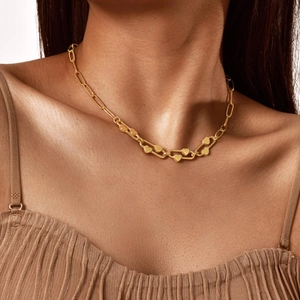 Detail of a polished gold heart pendant on a minimalist paperclip chain link necklace