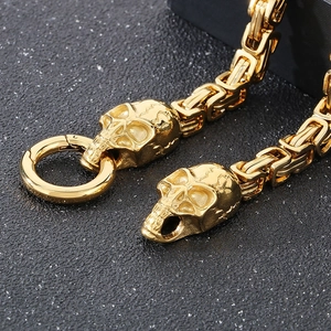 Macro detail of gold-plated skull ends and circular spring clasp on the woven steel chain