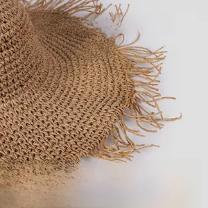 Close-up of handwoven paper straw sun hat featuring fringe edges and built-in shaping wire